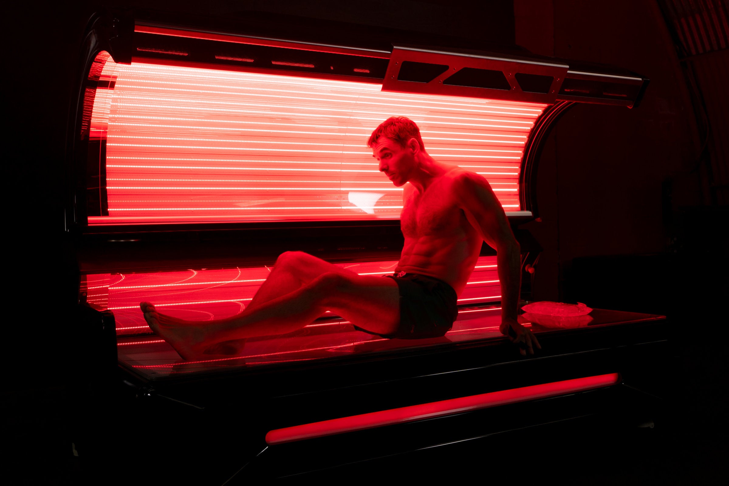 A man prepares to enter the red light bed, emphasizing that the bed is suitable for all genders. His physique showcases how the therapy aids in muscle recovery and wellness.