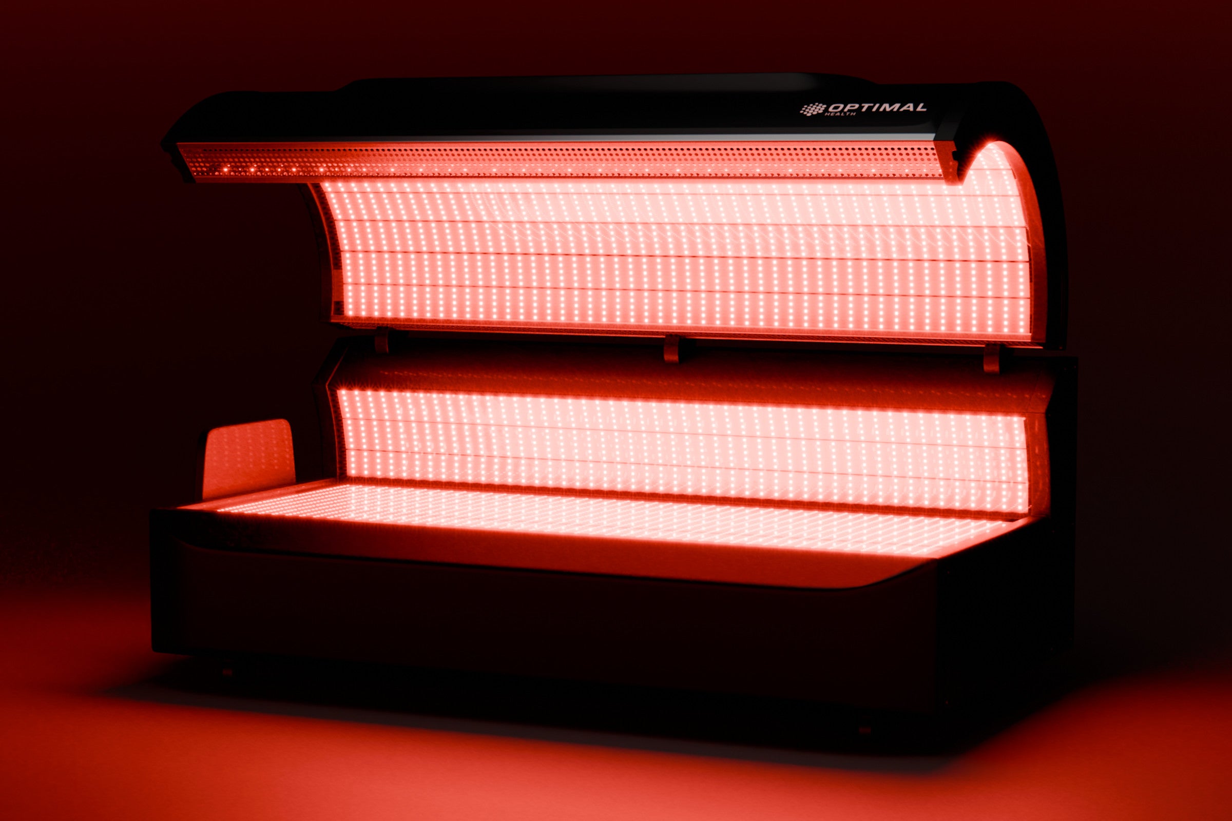 The red light bed is fully lit, demonstrating its operation. It showcases the powerful multi-wavelength LED lights, creating a therapeutic environment designed to promote skin rejuvenation, pain relief, and overall health benefits.