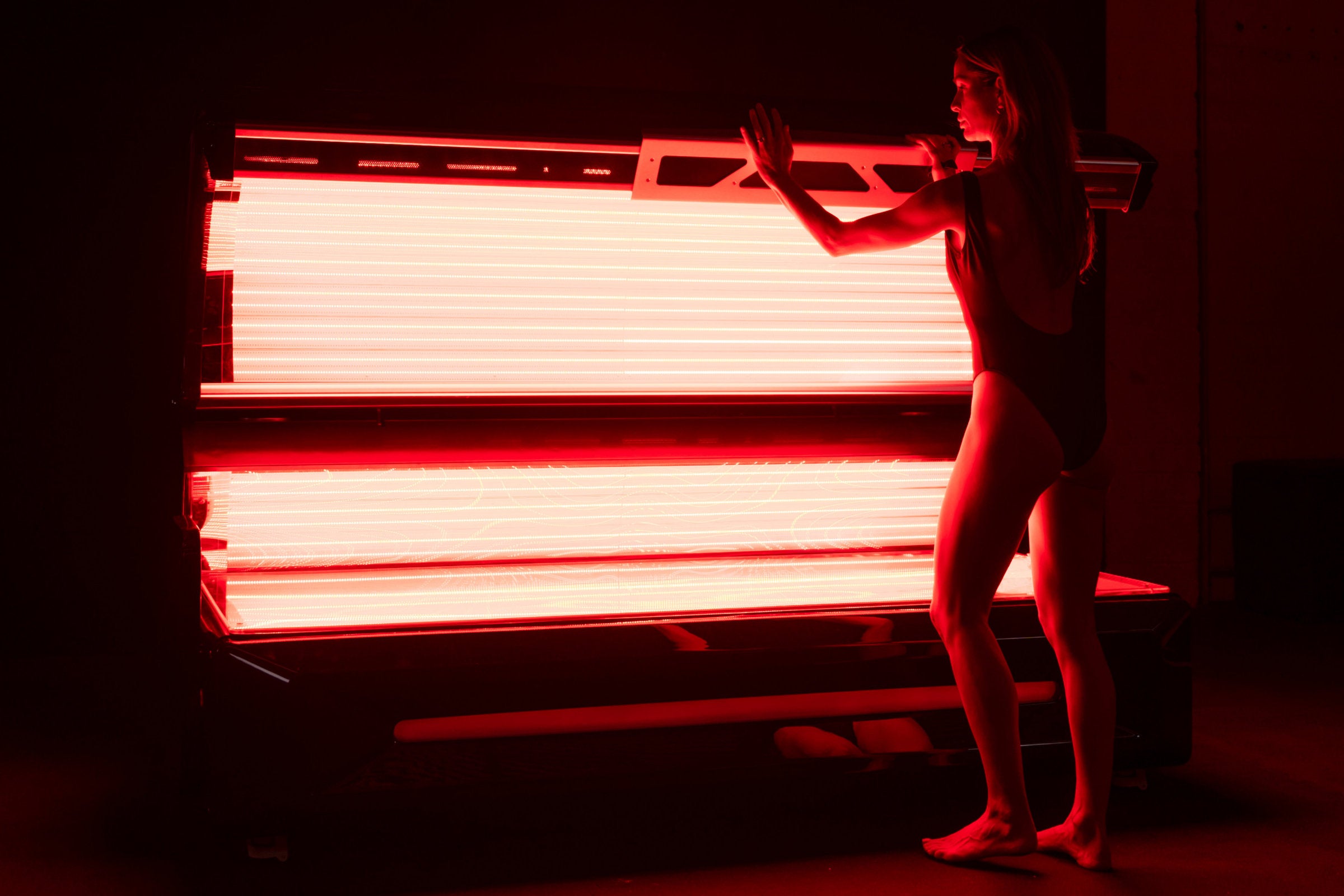 A person demonstrates how to open the red light bed, showing the internal lighting of the bed’s adjustable panels. This image focuses on the ergonomic design and ease of use.